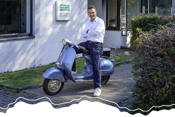 Chef Jan Szielasko auf einem Vespa-Roller vor dem Firmengebäude